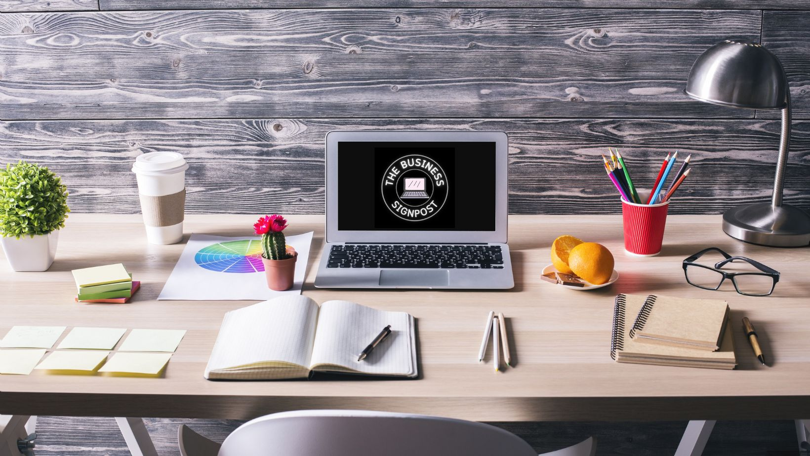 The Business Signpost header showing a desk with a laptop, notebook, pens etc.